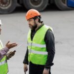 Two workers discussing essential safety tips to follow when handling skip hire
